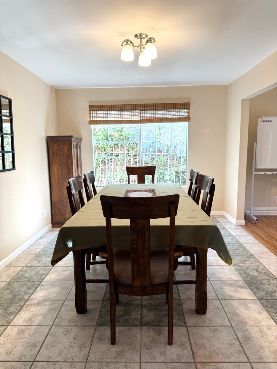 The dining room, with a long wooden table, six chairs and a garden window