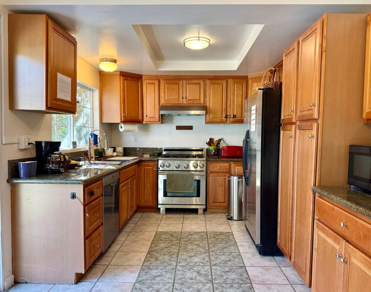The kitchen, with wood cabinets, granite counters, a gas range and a garden window